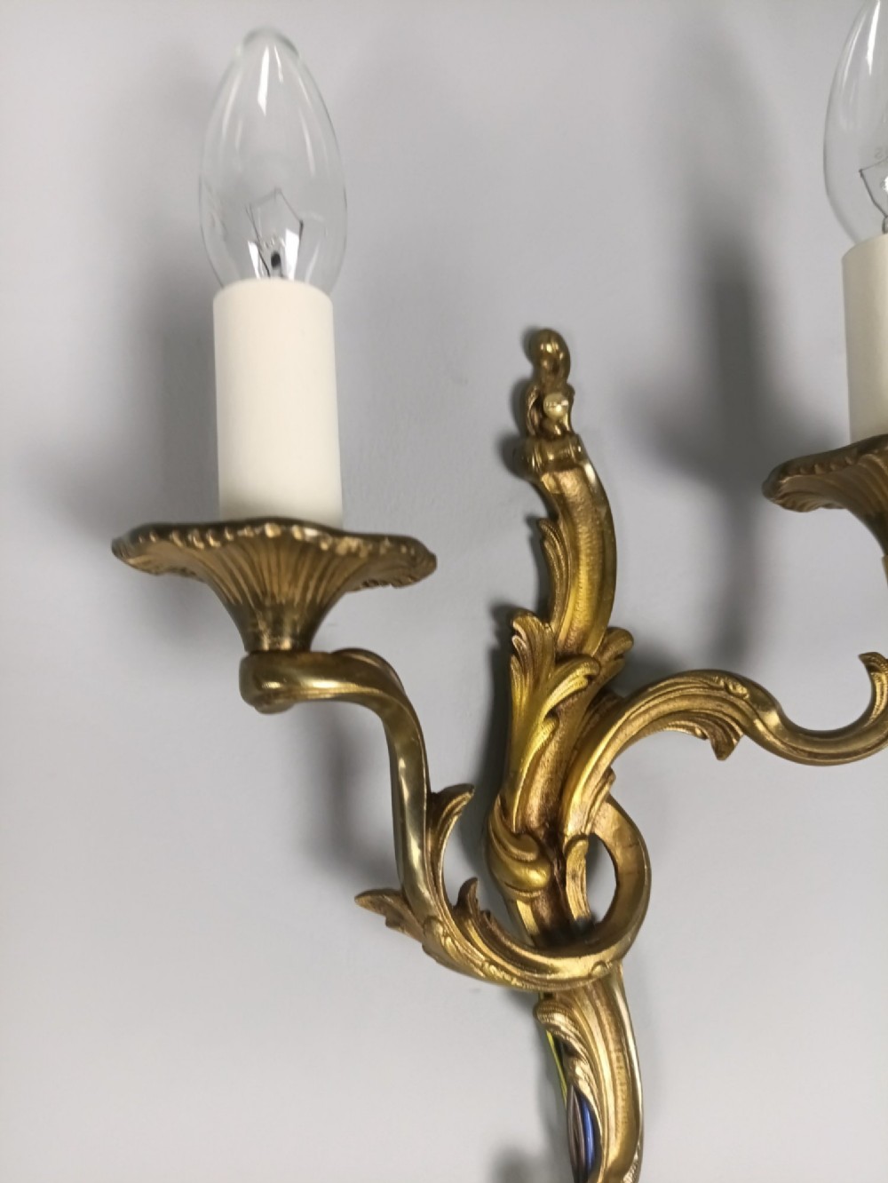 A set of three French gilded bronze twin-arm wall lights with ornate foliage scrolling and candle-style sockets. View VIII