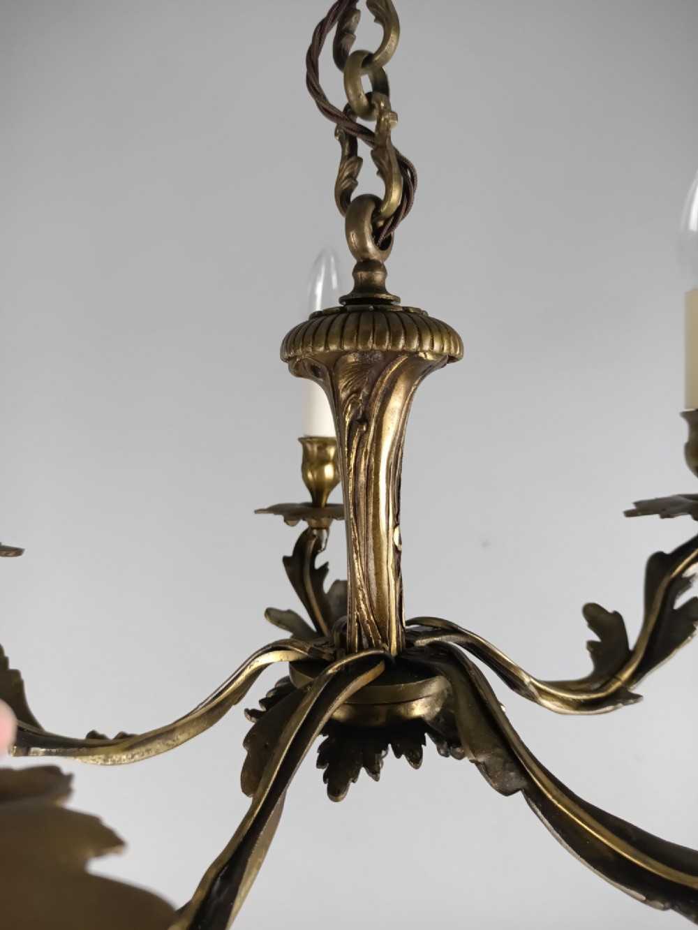 A five-arm dark bronze chandelier with cast acanthus leaf arms, white candle sleeves, and a matching hanging chain with ceiling rose. View VI