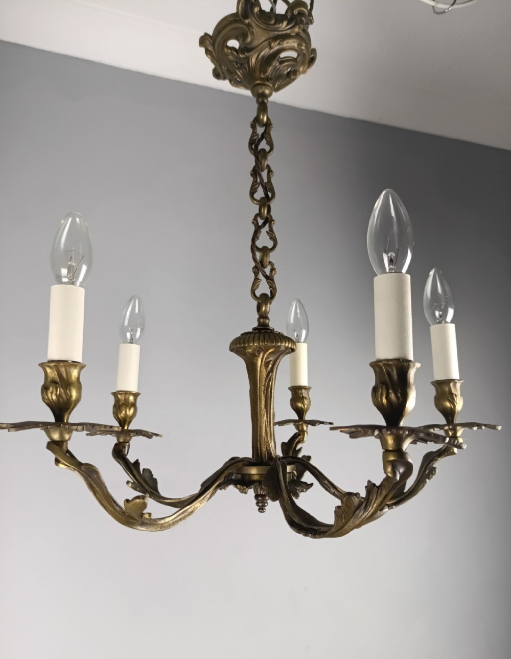A five-arm dark bronze chandelier with cast acanthus leaf arms, white candle sleeves, and a matching hanging chain with ceiling rose. View VIII