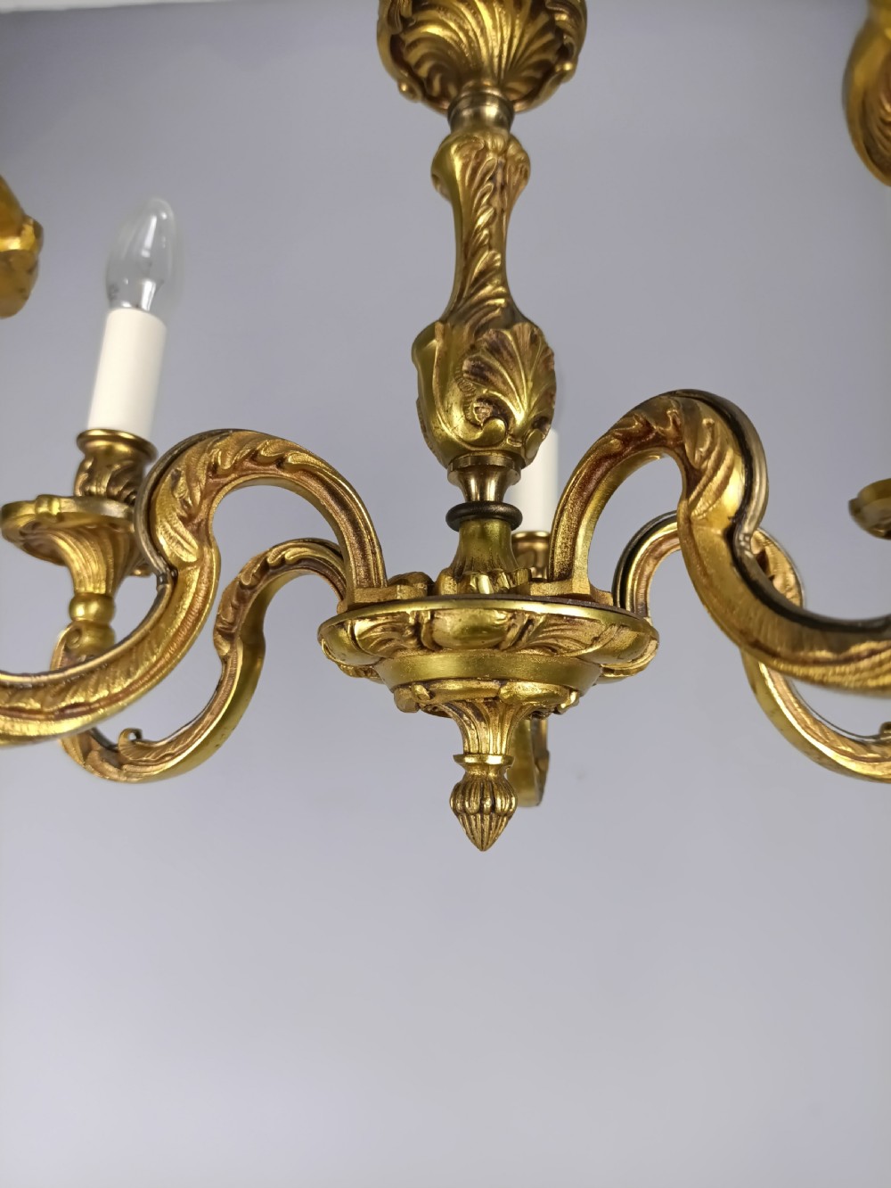A five-arm French gilt bronze chandelier featuring acanthus leaf scroll arms, candle-style sockets, and an ornate central column suspended by a chain. View V