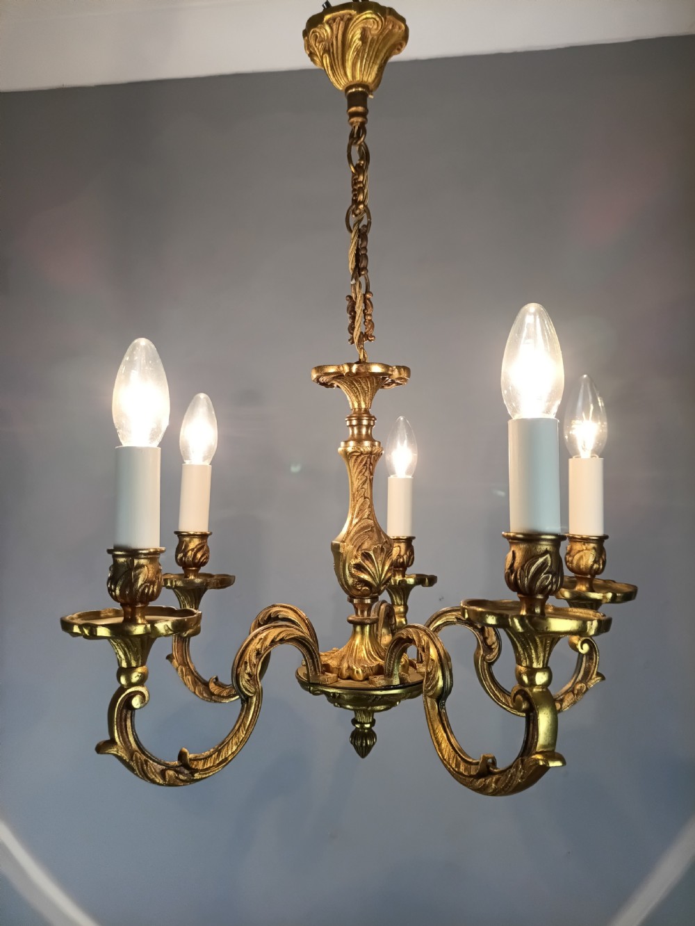 A five-arm French gilt bronze chandelier featuring acanthus leaf scroll arms, candle-style sockets, and an ornate central column suspended by a chain. View IX