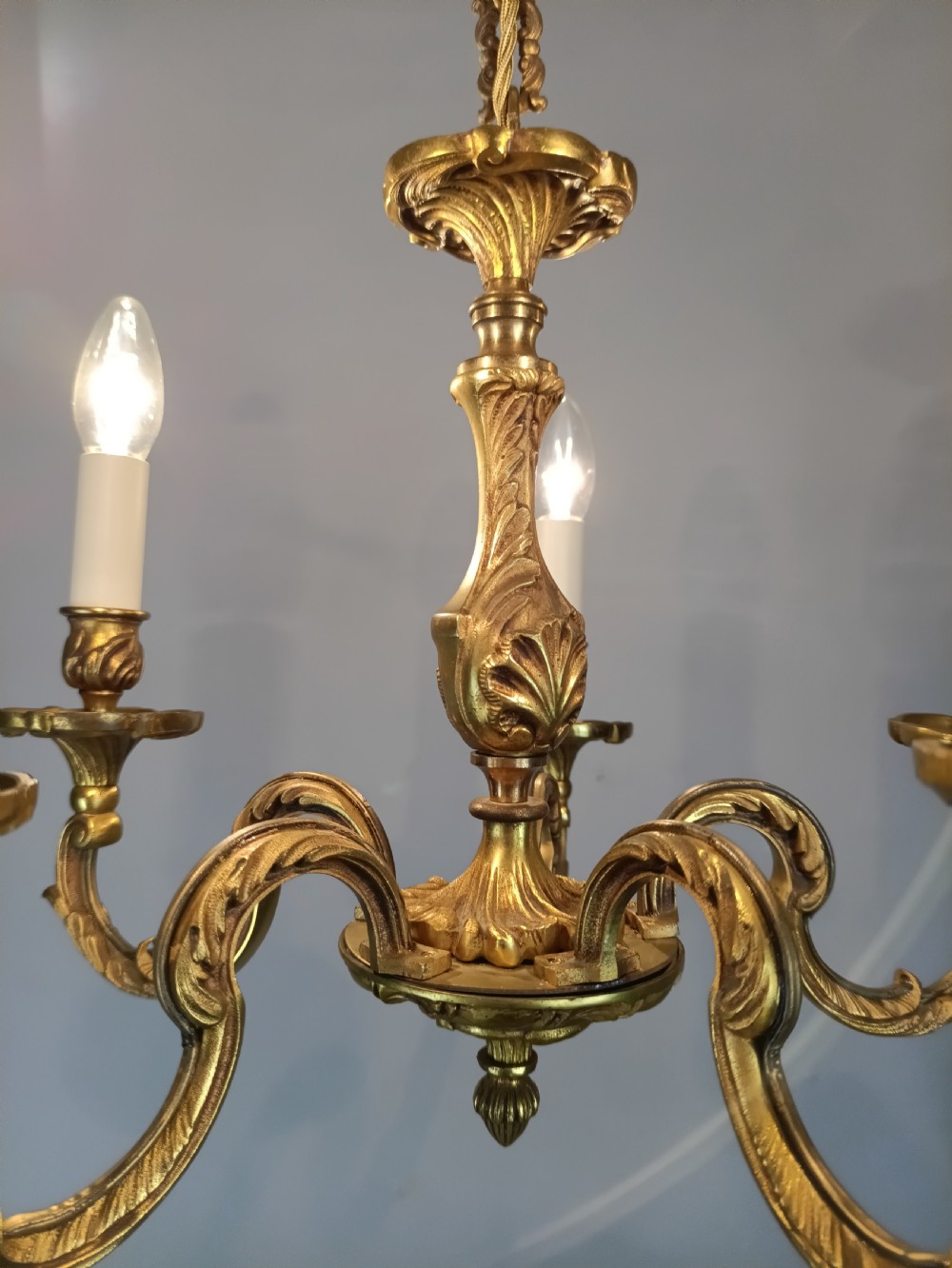 A five-arm French gilt bronze chandelier featuring acanthus leaf scroll arms, candle-style sockets, and an ornate central column suspended by a chain. View XI