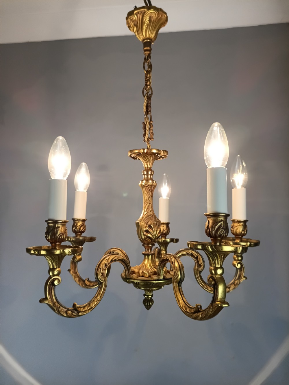 A five-arm French gilt bronze chandelier featuring acanthus leaf scroll arms, candle-style sockets, and an ornate central column suspended by a chain. View XIV