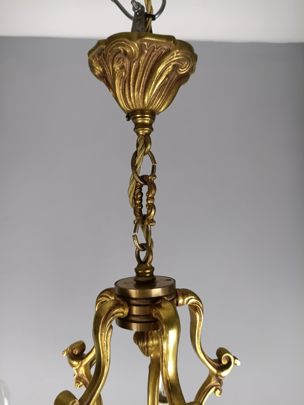 A French five-light gilt bronze birdcage chandelier featuring open rococo scrollwork arms, leafy candle drip pans, and a central open frame suspended by a chain. View III