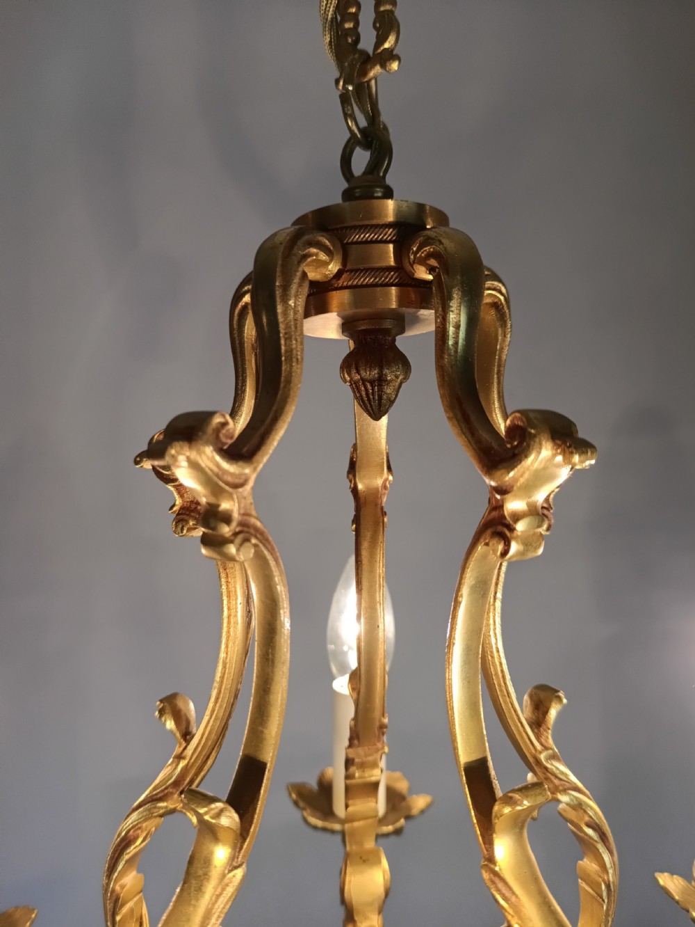 A French five-light gilt bronze birdcage chandelier featuring open rococo scrollwork arms, leafy candle drip pans, and a central open frame suspended by a chain. View XI