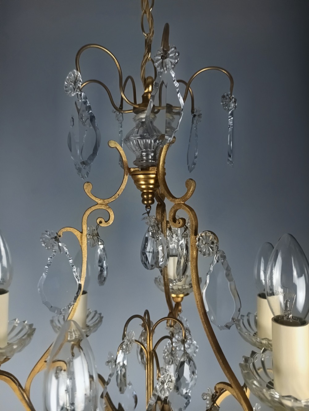 A French six-light birdcage chandelier featuring a gilded scroll frame decorated with clear faceted crystal drops and glass candle drip pans. View II