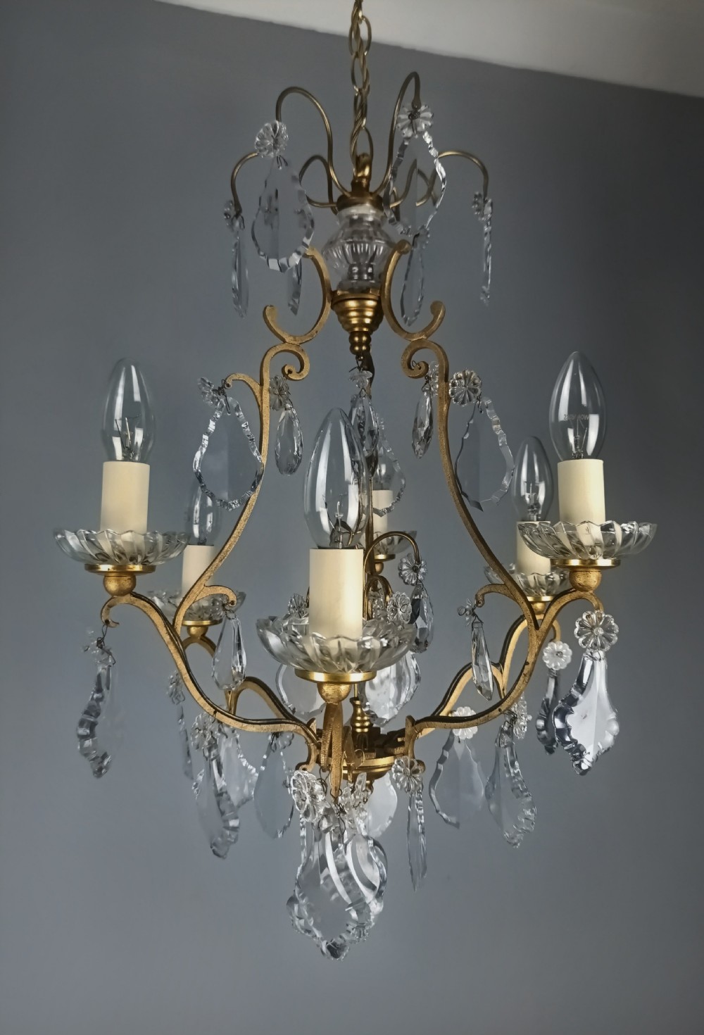 A French six-light birdcage chandelier featuring a gilded scroll frame decorated with clear faceted crystal drops and glass candle drip pans. View III