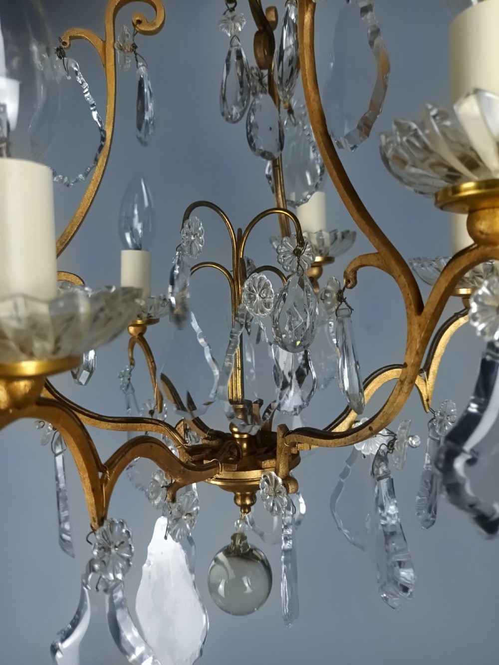 A French six-light birdcage chandelier featuring a gilded scroll frame decorated with clear faceted crystal drops and glass candle drip pans. View IV