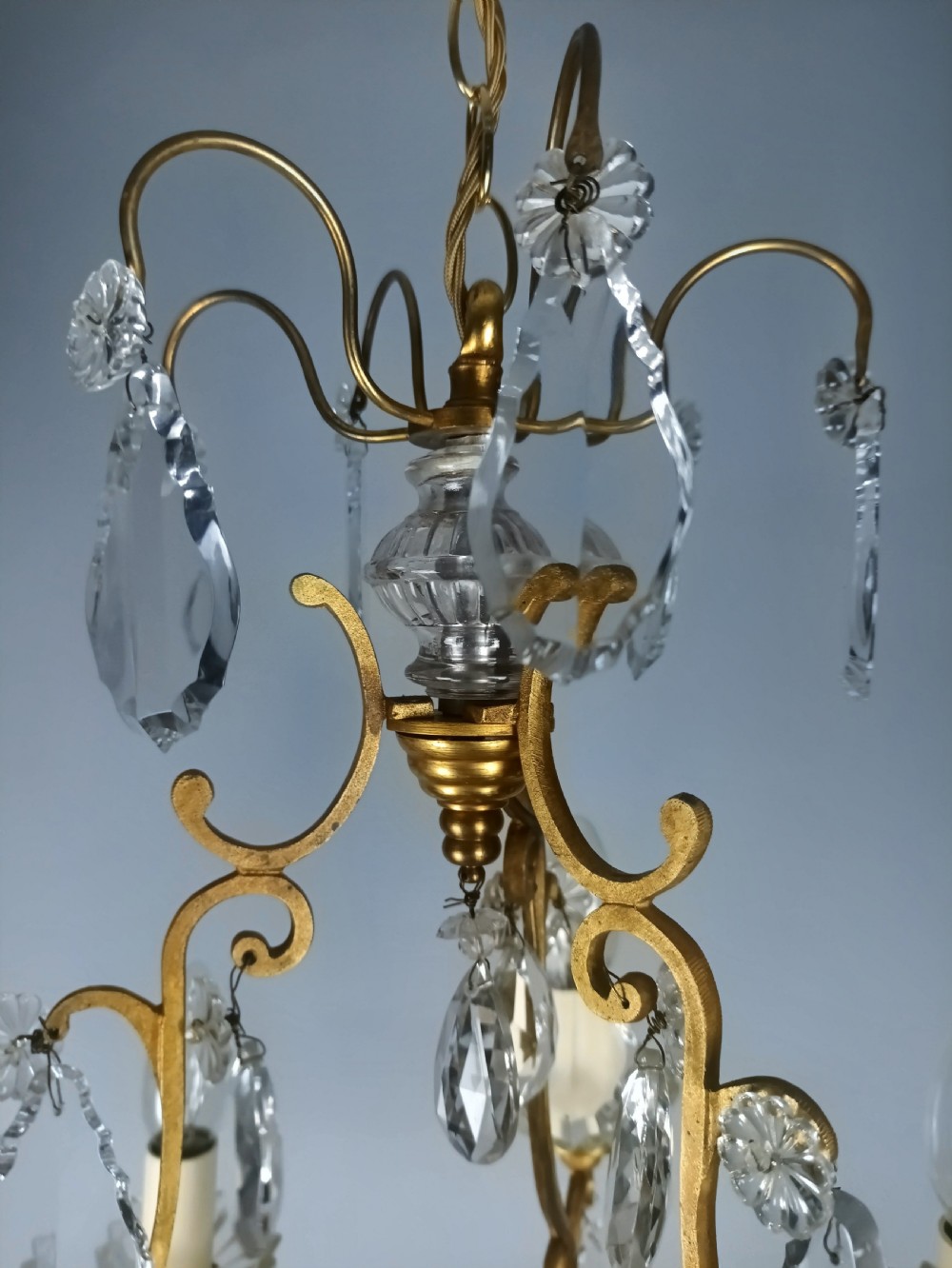 A French six-light birdcage chandelier featuring a gilded scroll frame decorated with clear faceted crystal drops and glass candle drip pans. View V