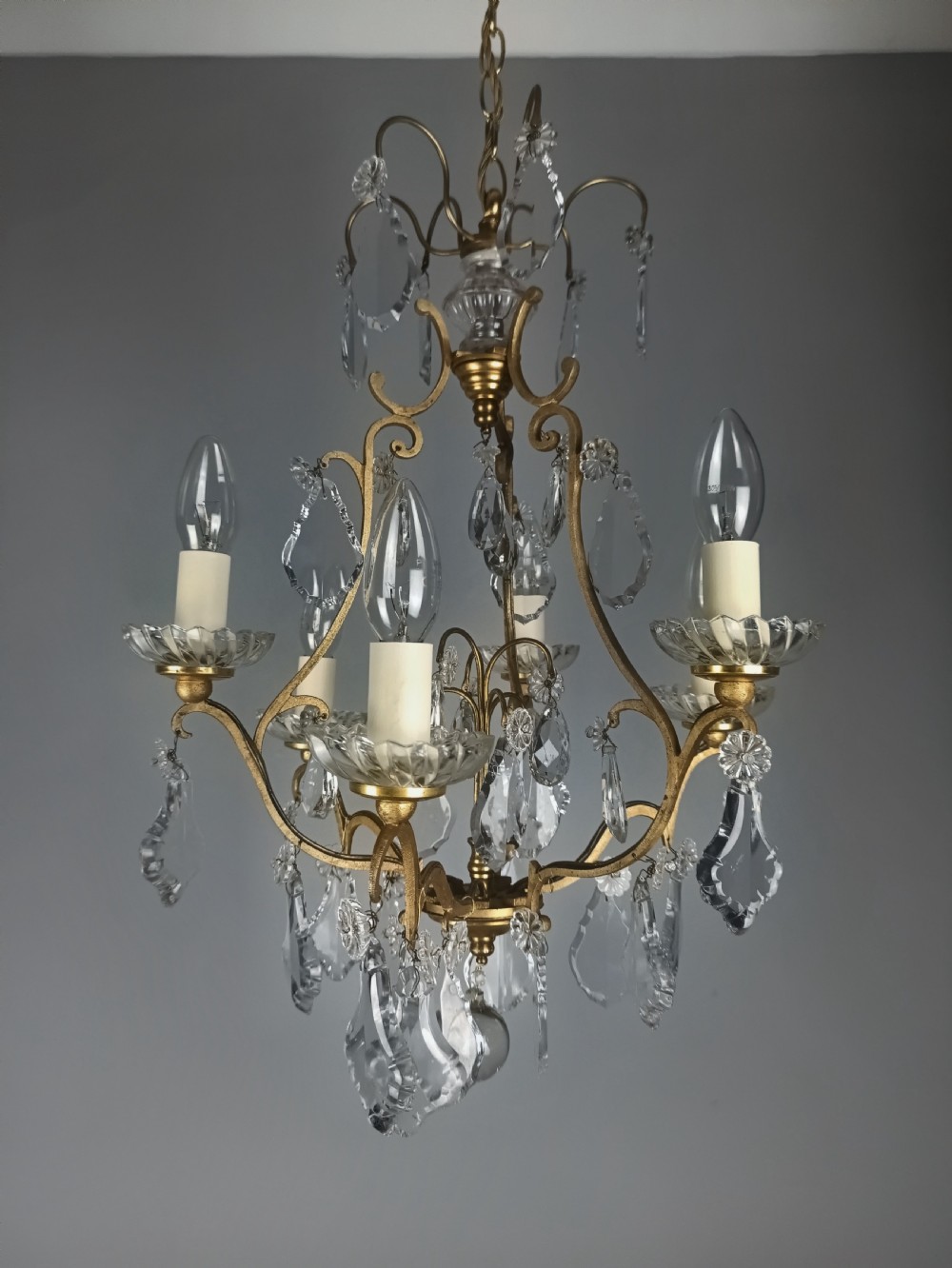 A French six-light birdcage chandelier featuring a gilded scroll frame decorated with clear faceted crystal drops and glass candle drip pans. View VII