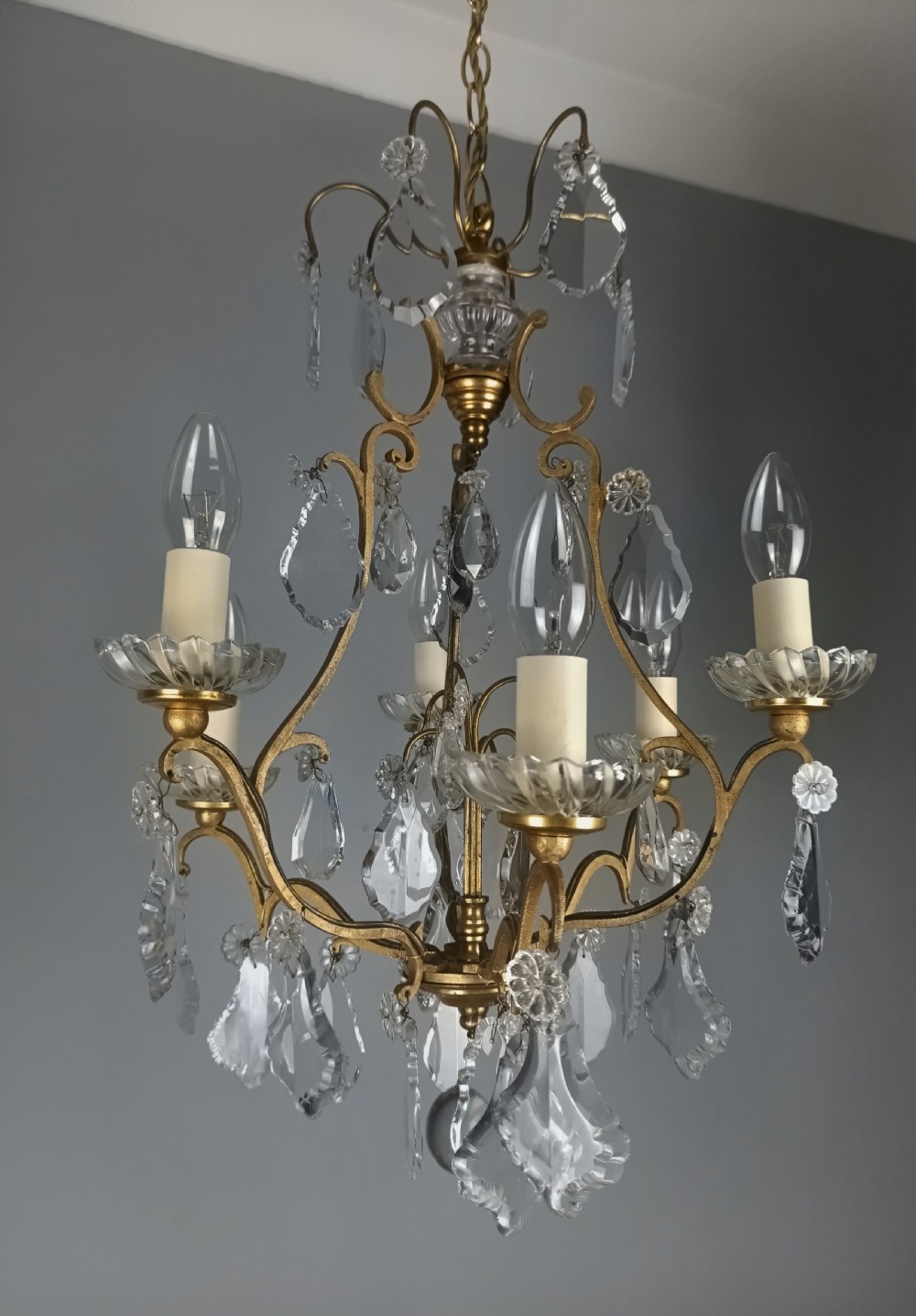 A French six-light birdcage chandelier featuring a gilded scroll frame decorated with clear faceted crystal drops and glass candle drip pans. View VIII