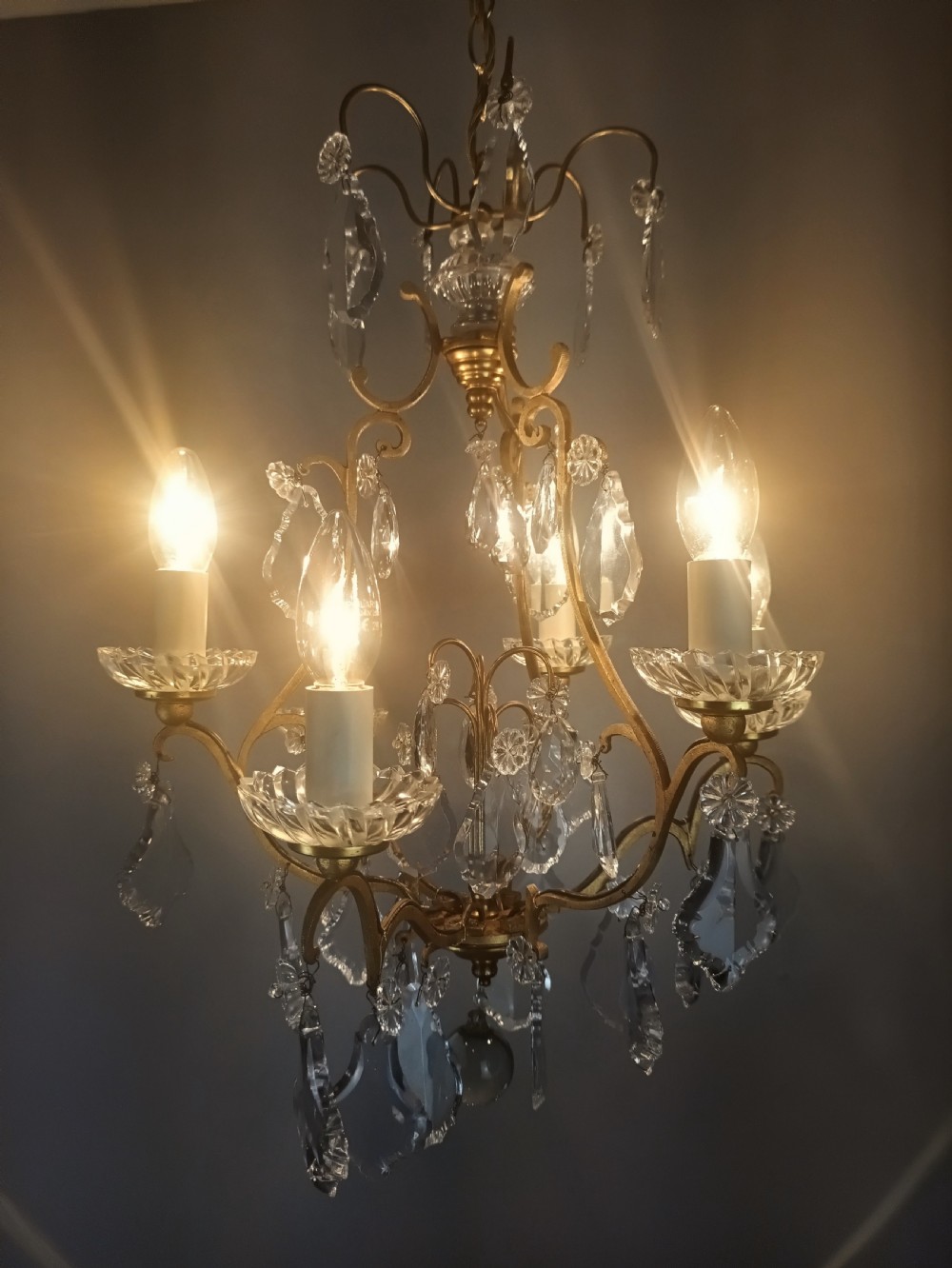 A French six-light birdcage chandelier featuring a gilded scroll frame decorated with clear faceted crystal drops and glass candle drip pans. View IX