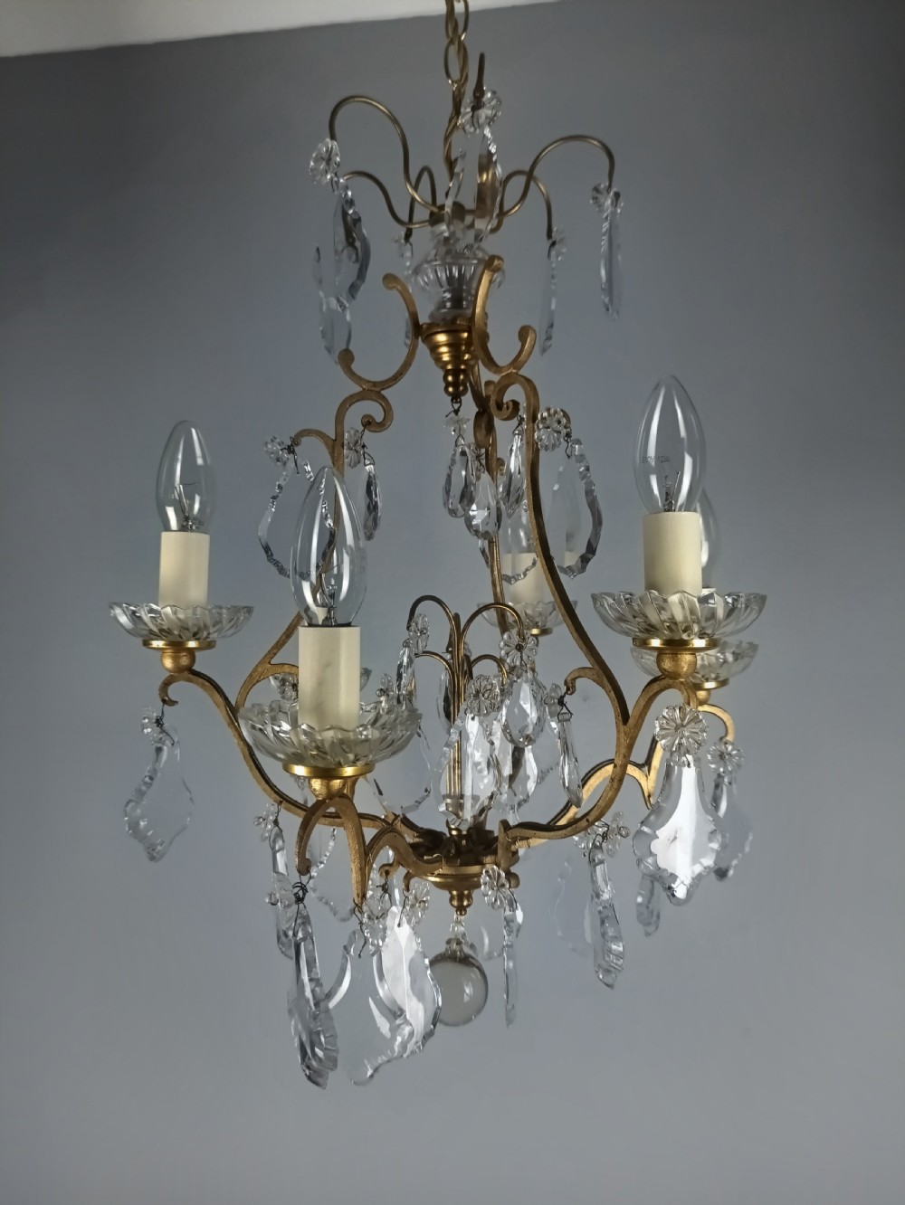 A French six-light birdcage chandelier featuring a gilded scroll frame decorated with clear faceted crystal drops and glass candle drip pans. View XI
