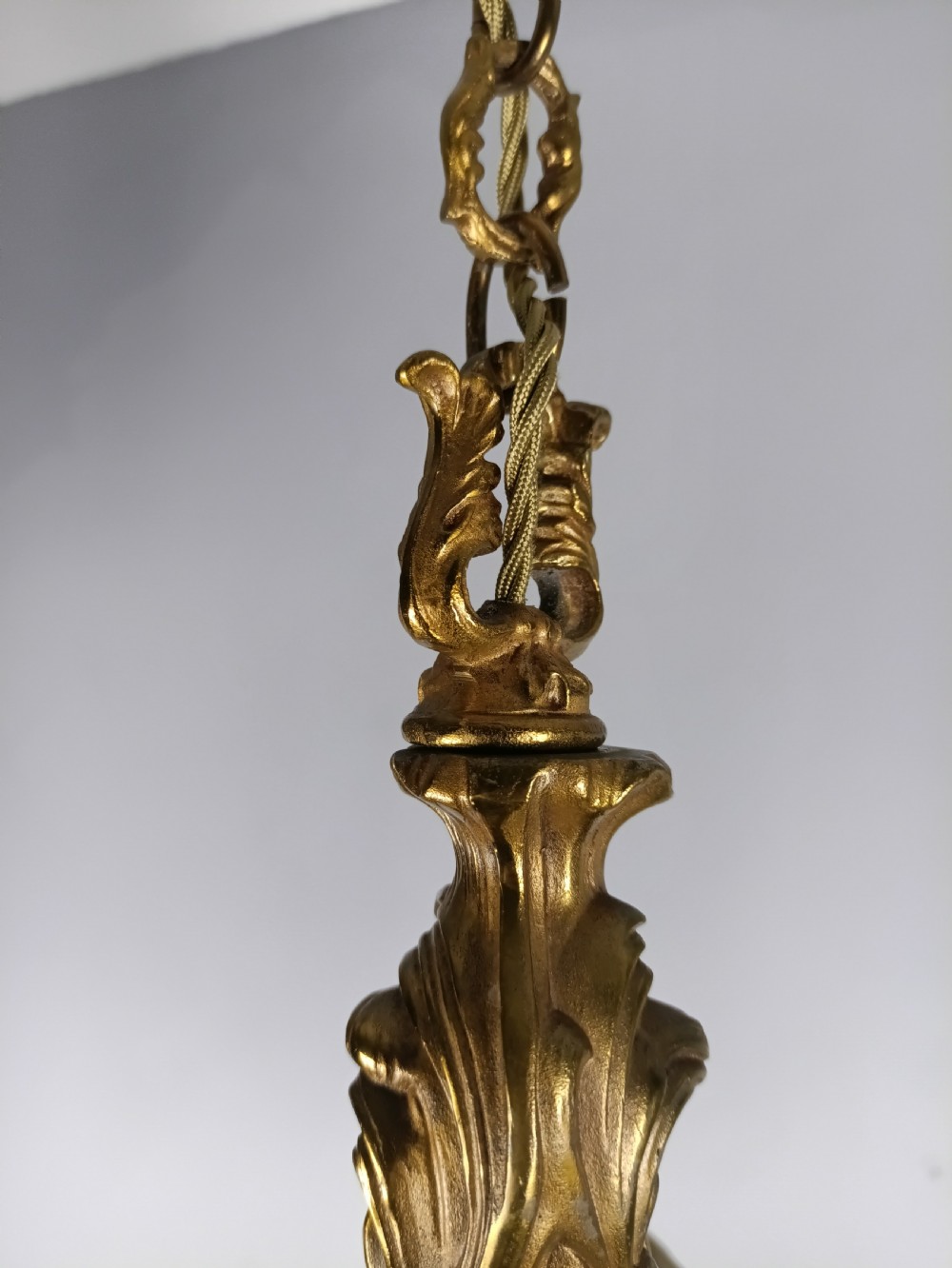 A French six-light gilt bronze chandelier featuring scrolling acanthus leaf arms, candle-style bulb sleeves, and an ornamental central stem suspended from a chain. View VI