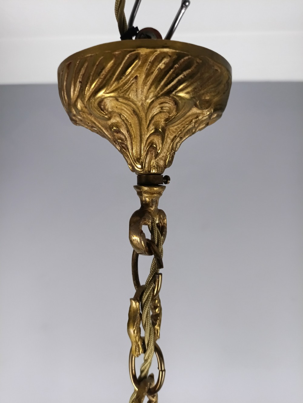 A French six-light gilt bronze chandelier featuring scrolling acanthus leaf arms, candle-style bulb sleeves, and an ornamental central stem suspended from a chain. View VII