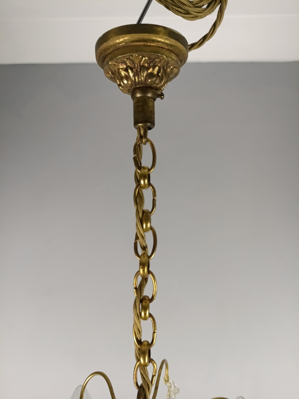 A four-arm brass mini chandelier featuring clear glass droplets, floral bobeches, and a central glass stem column. View VI