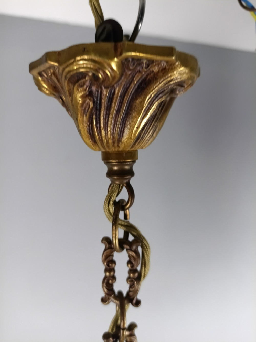 A four-arm French gilt metal chandelier decorated with scrolling arms, candle-style light sockets, and hanging faceted cut crystal drops. View VIII
