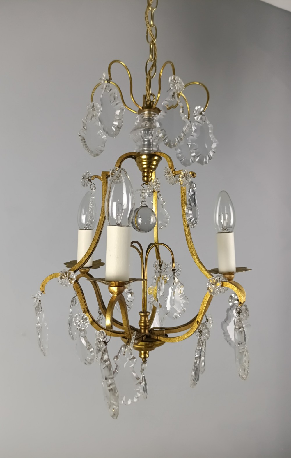 A French gilded metal three-arm birdcage chandelier with hanging clear crystal droplets and glass rosette accents. View III