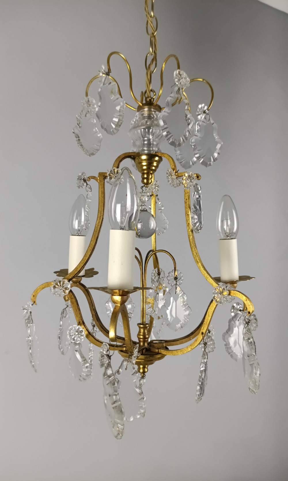 A French gilded metal three-arm birdcage chandelier with hanging clear crystal droplets and glass rosette accents. View IV