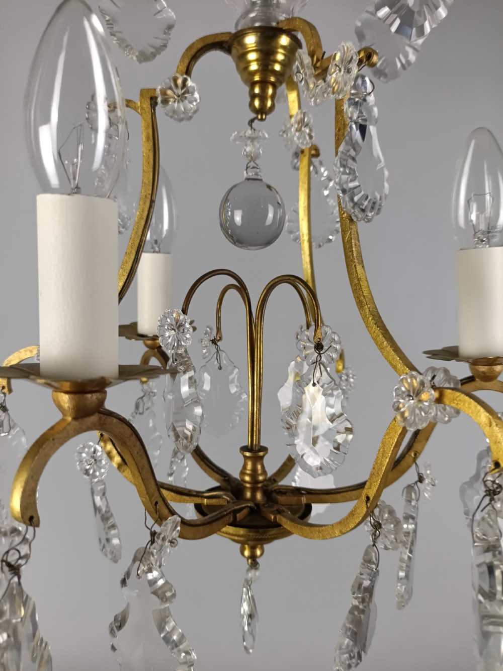 A French gilded metal three-arm birdcage chandelier with hanging clear crystal droplets and glass rosette accents. View VI