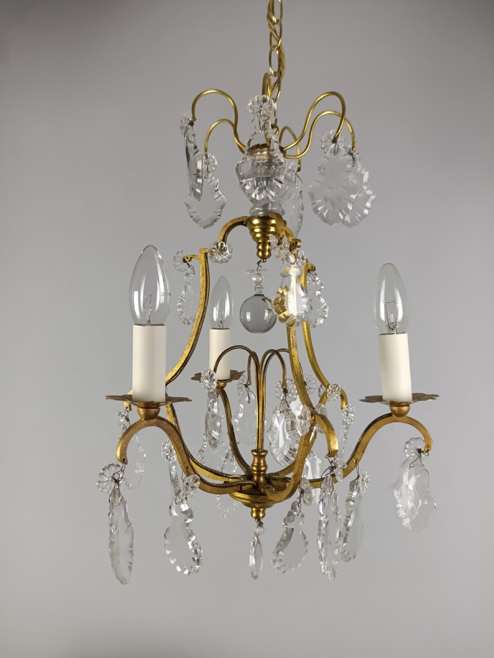 A French gilded metal three-arm birdcage chandelier with hanging clear crystal droplets and glass rosette accents. View IX