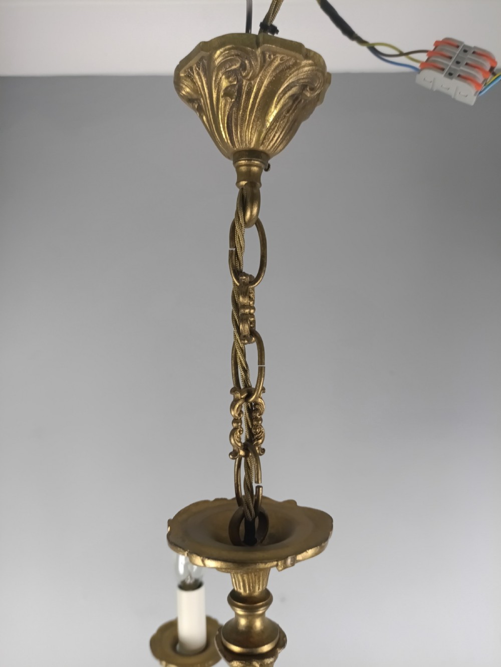 A French gilt brass five-arm chandelier featuring ornate scrolled branches, leaf motifs, and candle bulb sockets suspended from a central chain. View V