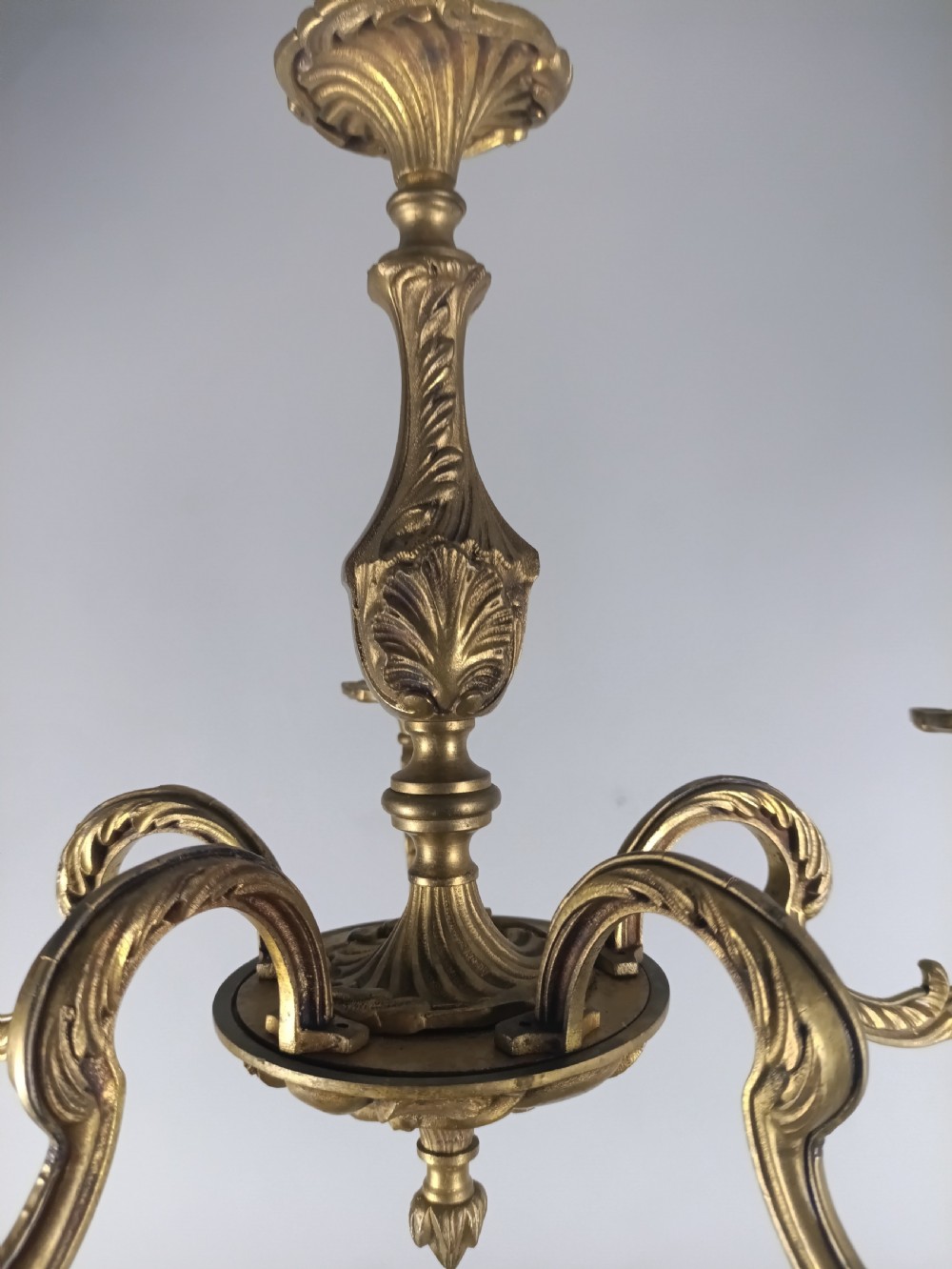 A French gilt brass five-arm chandelier featuring ornate scrolled branches, leaf motifs, and candle bulb sockets suspended from a central chain. View VI