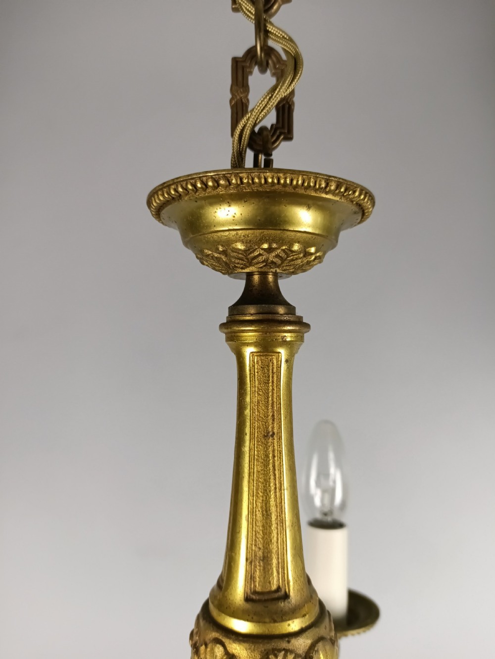 A three-arm gilt brass ceiling chandelier featuring scrolled branches, acanthus leaf decoration, and a central tapered column suspended by a chain. View VII
