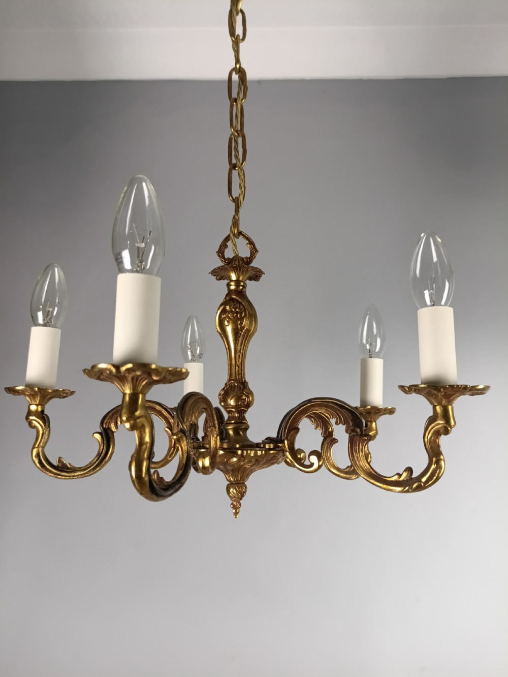 A French five-light gilt bronze chandelier featuring scrolling Rococo arms, candle-style bulb holders, and a central chased stem. View II