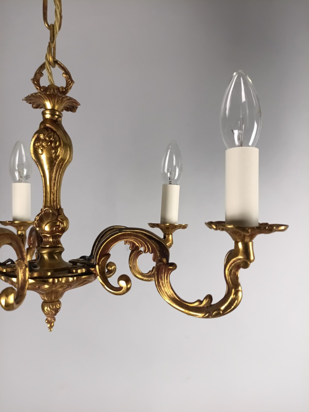 A French five-light gilt bronze chandelier featuring scrolling Rococo arms, candle-style bulb holders, and a central chased stem. View III