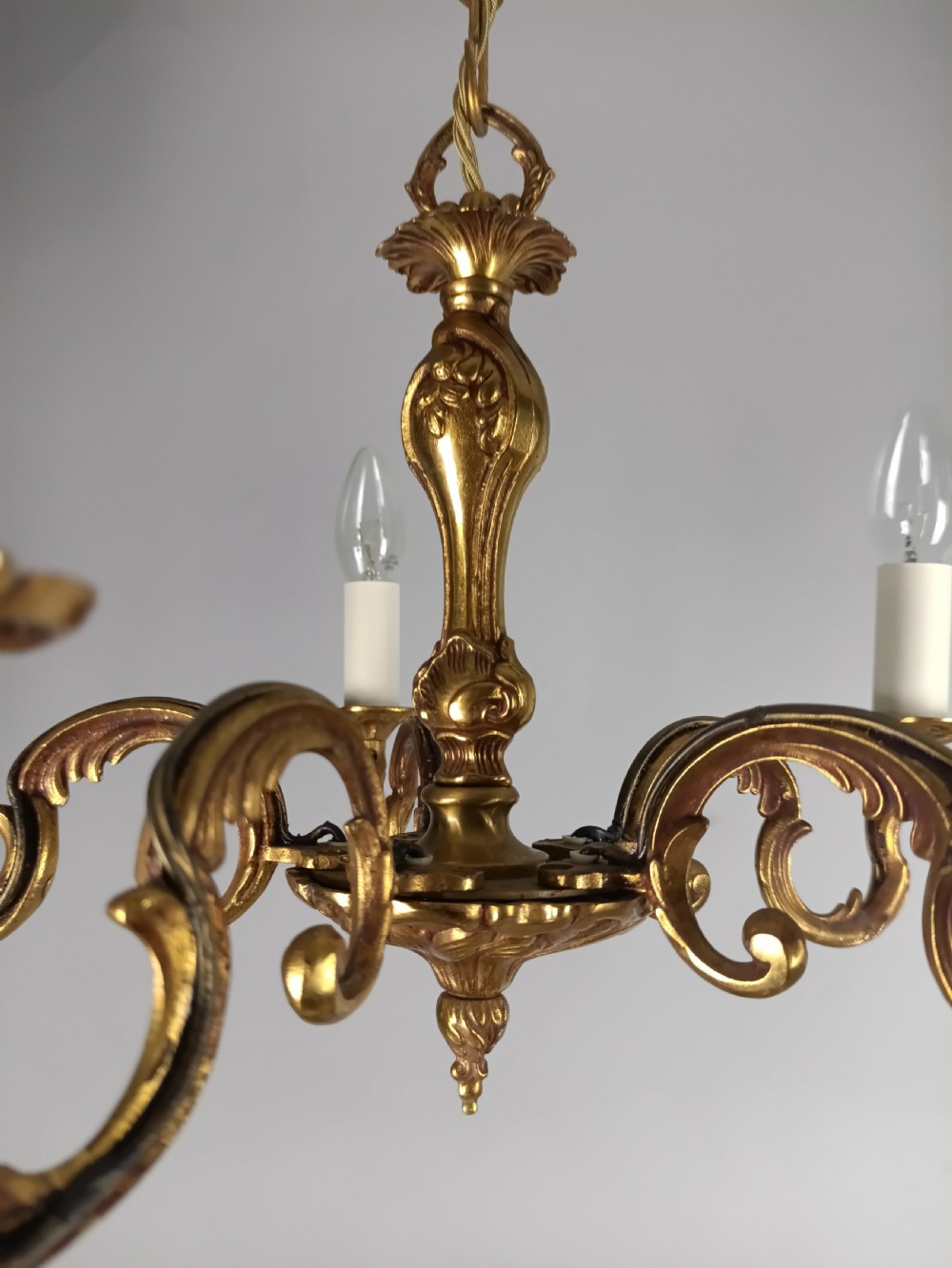 A French five-light gilt bronze chandelier featuring scrolling Rococo arms, candle-style bulb holders, and a central chased stem. View IV