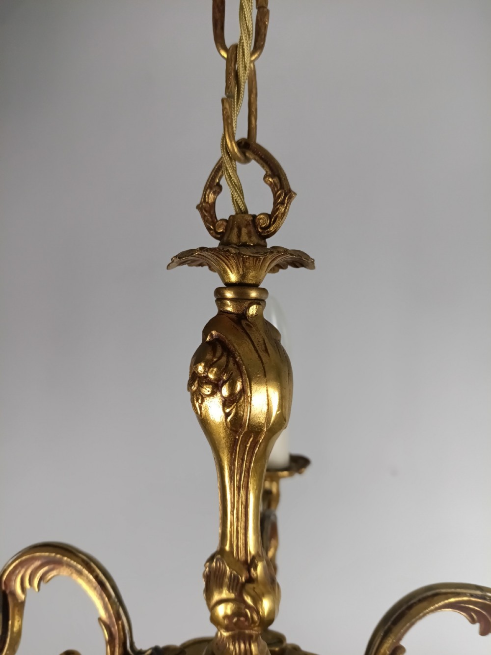 A French five-light gilt bronze chandelier featuring scrolling Rococo arms, candle-style bulb holders, and a central chased stem. View V