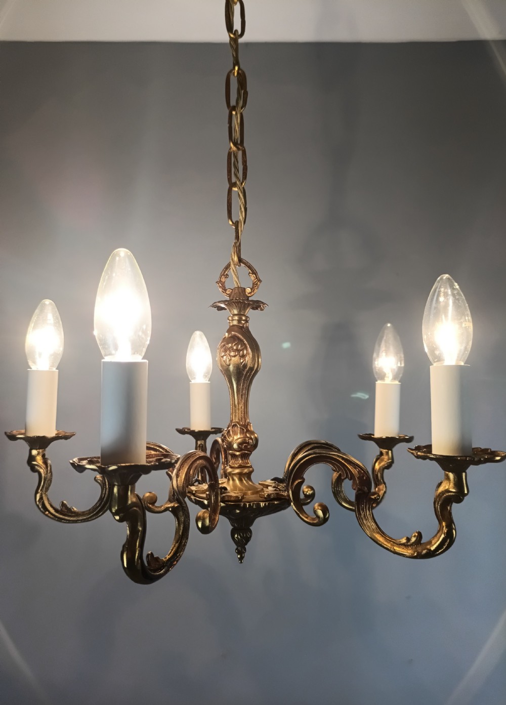 A French five-light gilt bronze chandelier featuring scrolling Rococo arms, candle-style bulb holders, and a central chased stem. View VIII