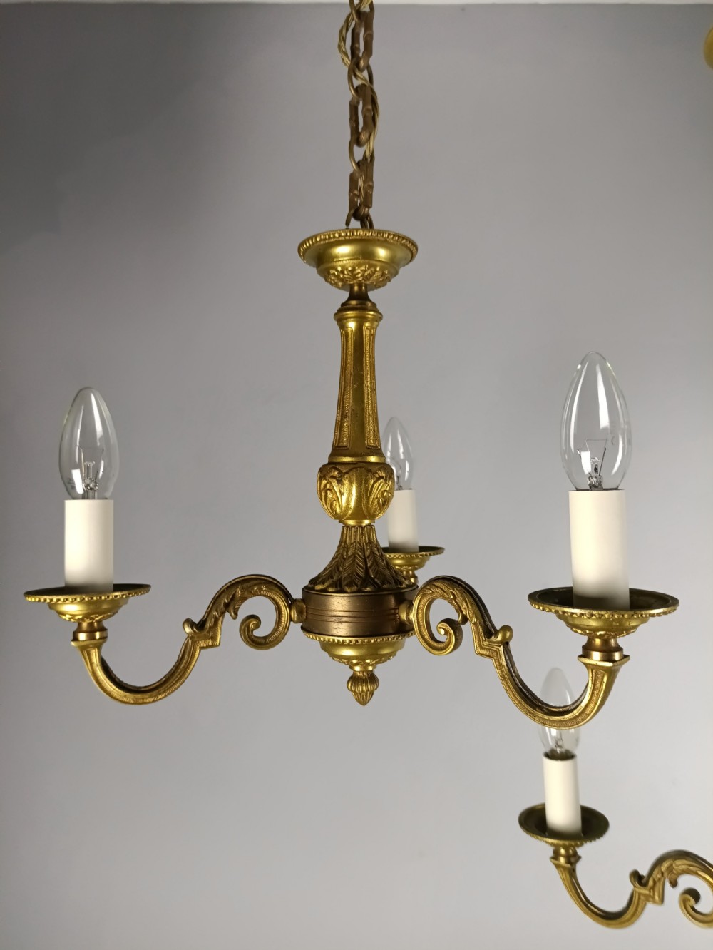A pair of French gilt brass three-arm chandeliers featuring scrolling branches and fluted central columns suspended from metal chains. View III