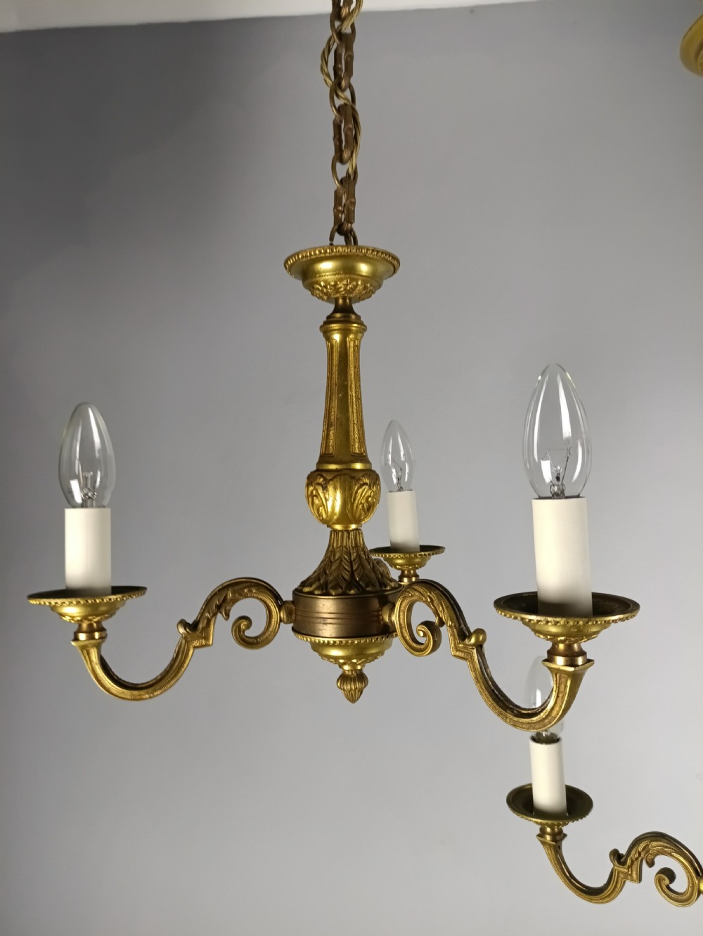 A pair of French gilt brass three-arm chandeliers featuring scrolling branches and fluted central columns suspended from metal chains. View VI