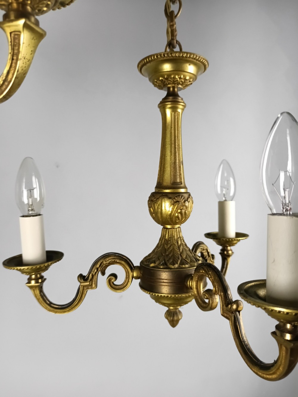 A pair of French gilt brass three-arm chandeliers featuring scrolling branches and fluted central columns suspended from metal chains. View VII