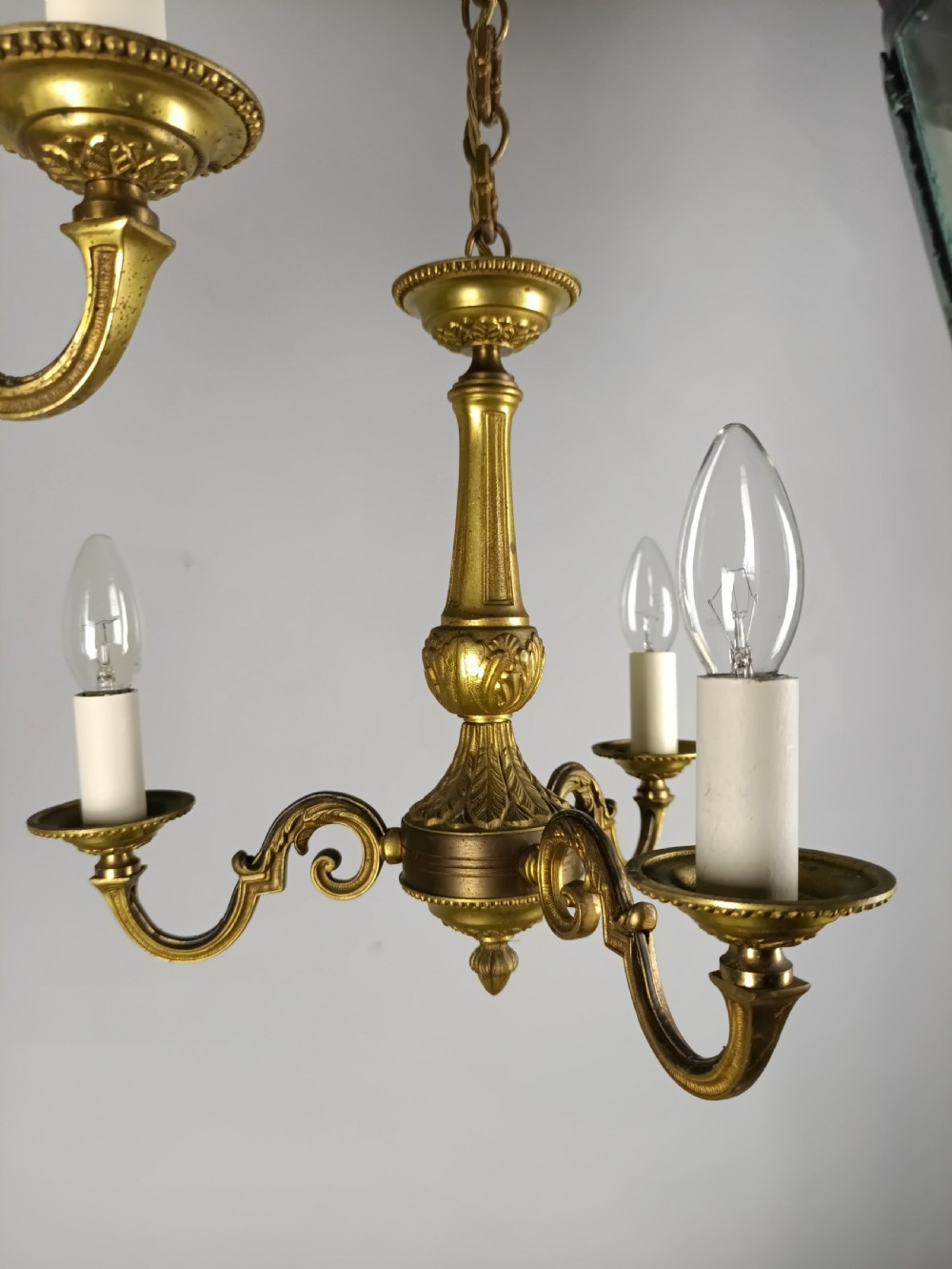 A pair of French gilt brass three-arm chandeliers featuring scrolling branches and fluted central columns suspended from metal chains. View VIII