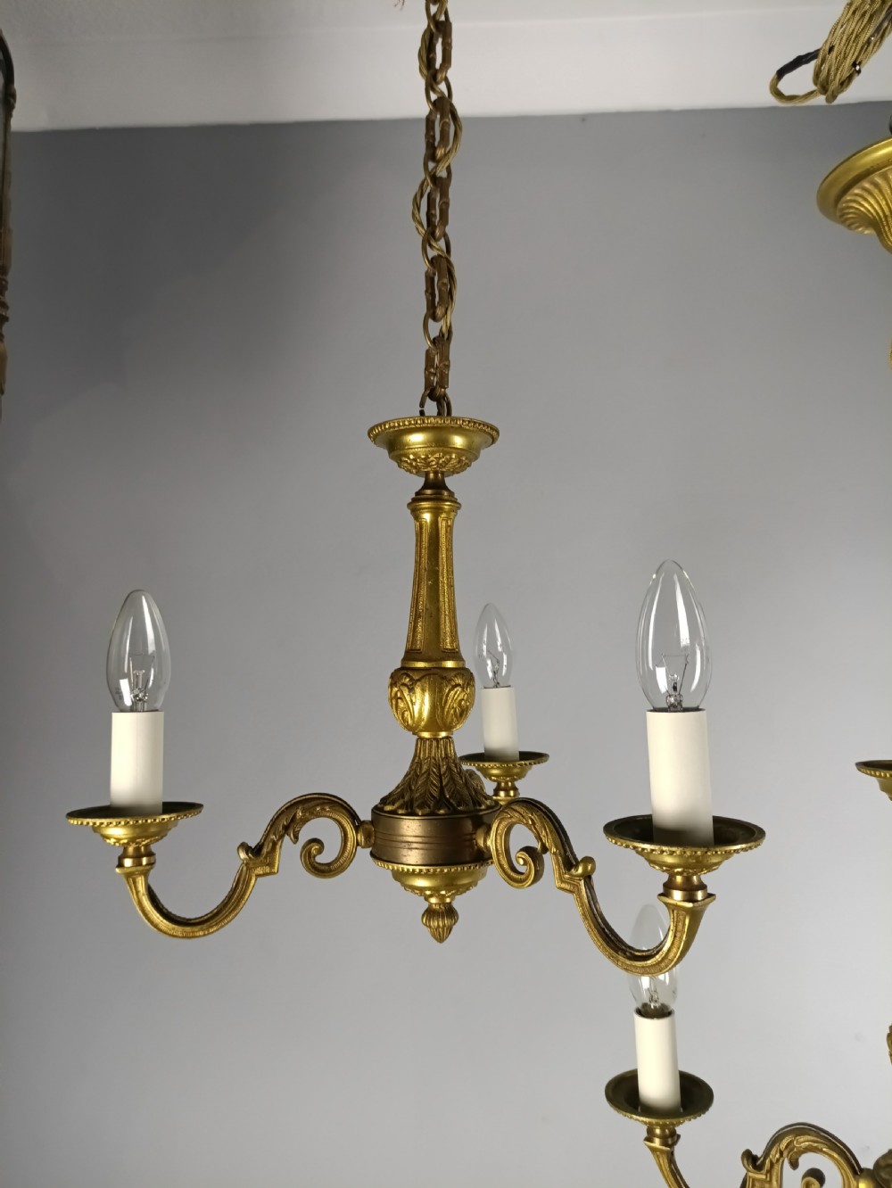 A pair of French gilt brass three-arm chandeliers featuring scrolling branches and fluted central columns suspended from metal chains. View IX