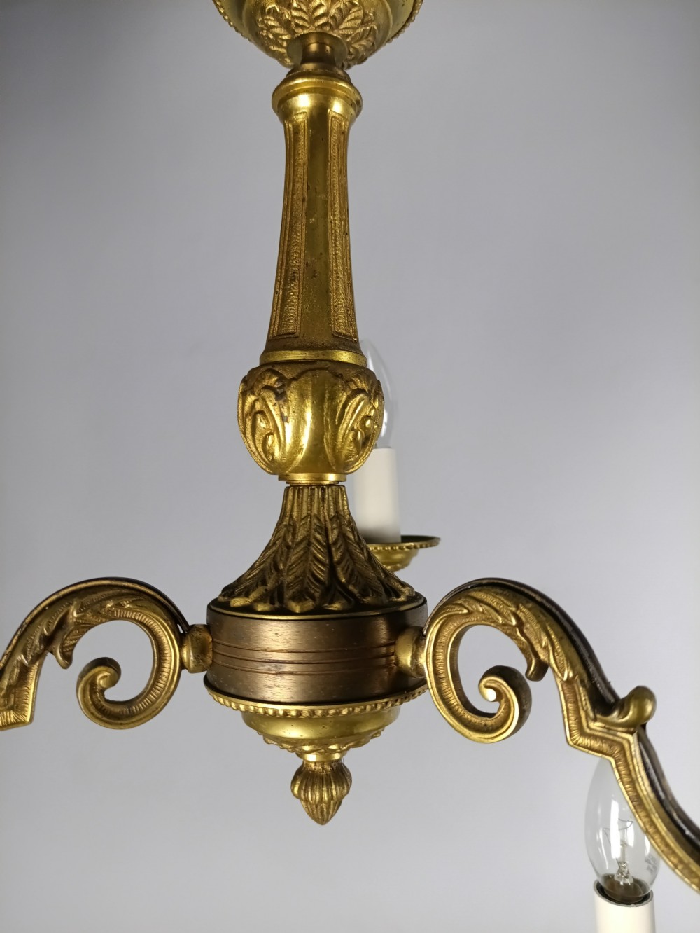A pair of French gilt brass three-arm chandeliers featuring scrolling branches and fluted central columns suspended from metal chains. View X