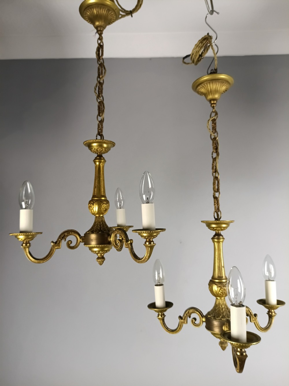 A pair of French gilt brass three-arm chandeliers featuring scrolling branches and fluted central columns suspended from metal chains. View XI