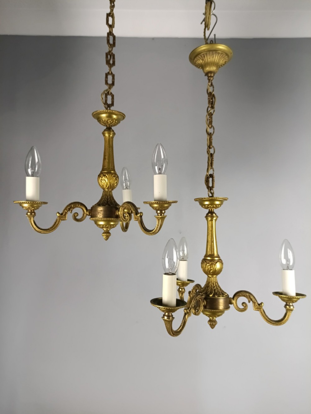 A pair of three-arm French gilt brass chandeliers featuring scrolling arms, central baluster shafts, and candle-style sockets. View II