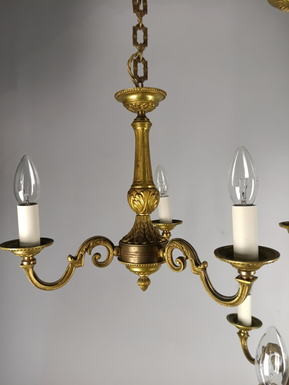 A pair of three-arm French gilt brass chandeliers featuring scrolling arms, central baluster shafts, and candle-style sockets. View III