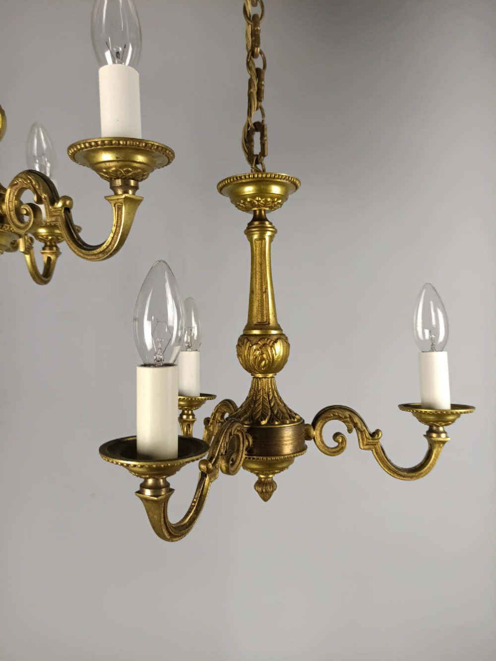 A pair of three-arm French gilt brass chandeliers featuring scrolling arms, central baluster shafts, and candle-style sockets. View IV