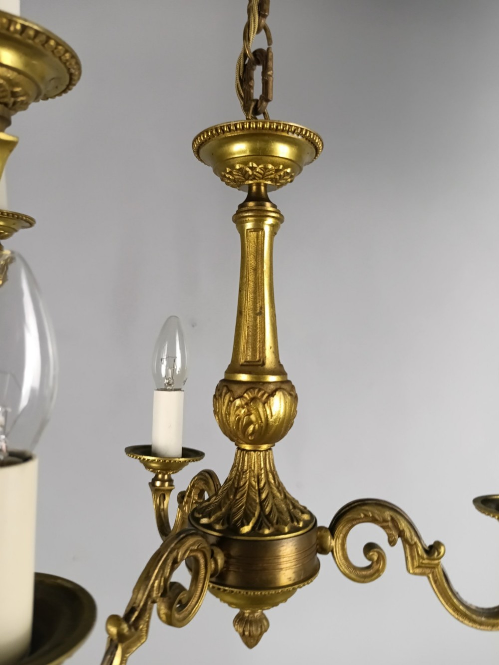 A pair of three-arm French gilt brass chandeliers featuring scrolling arms, central baluster shafts, and candle-style sockets. View V