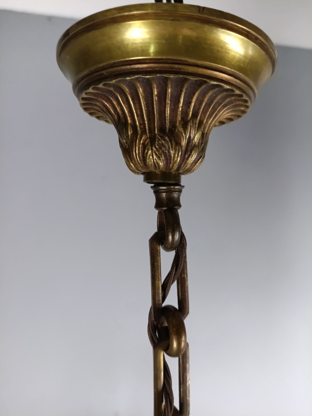 A French antique-style bronze six-arm chandelier featuring scrolling candle arms, white candle sleeves, and a central urn-shaped stem suspended from a metal chain. View VI