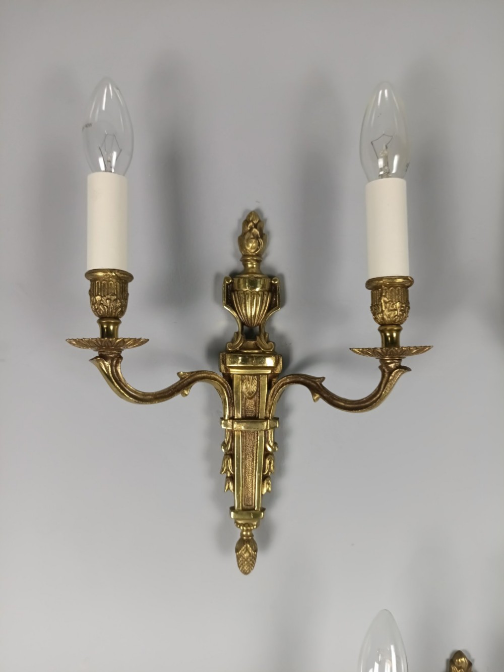 Set of three French Louis XVI style twin-arm wall lights in gilded metal with urn backplates and fluted shafts. View III