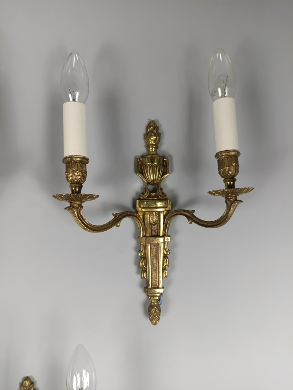 Set of three French Louis XVI style twin-arm wall lights in gilded metal with urn backplates and fluted shafts. View IV