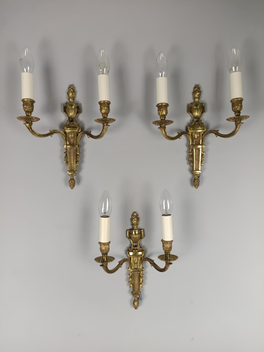 Set of three French Louis XVI style twin-arm wall lights in gilded metal with urn backplates and fluted shafts. View VI