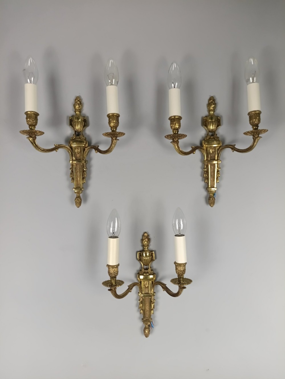 Set of three French Louis XVI style twin-arm wall lights in gilded metal with urn backplates and fluted shafts. View VII