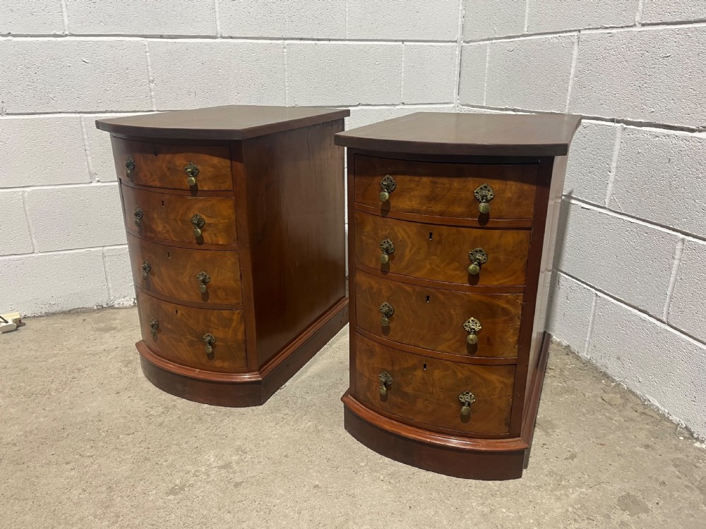 A pair of 19th-century mahogany bedside chests with curved bowfront drawers and ornamental brass drop handles.